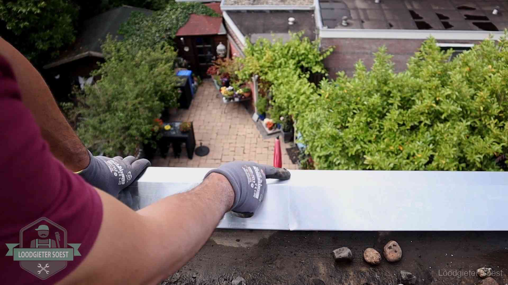 Vakman plaatst een daktrim op de dakrand van een woning in Soest