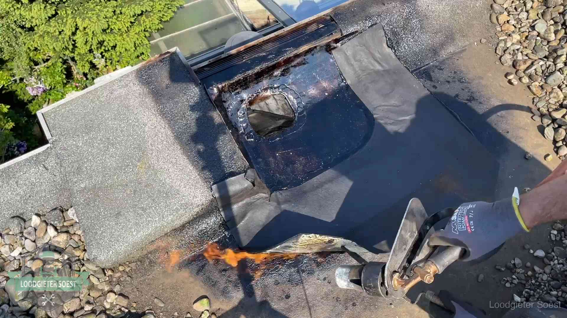 Dakdekker brandt bitumen rond een doorvoer tijdens een daklekkage-reparatie in Soest