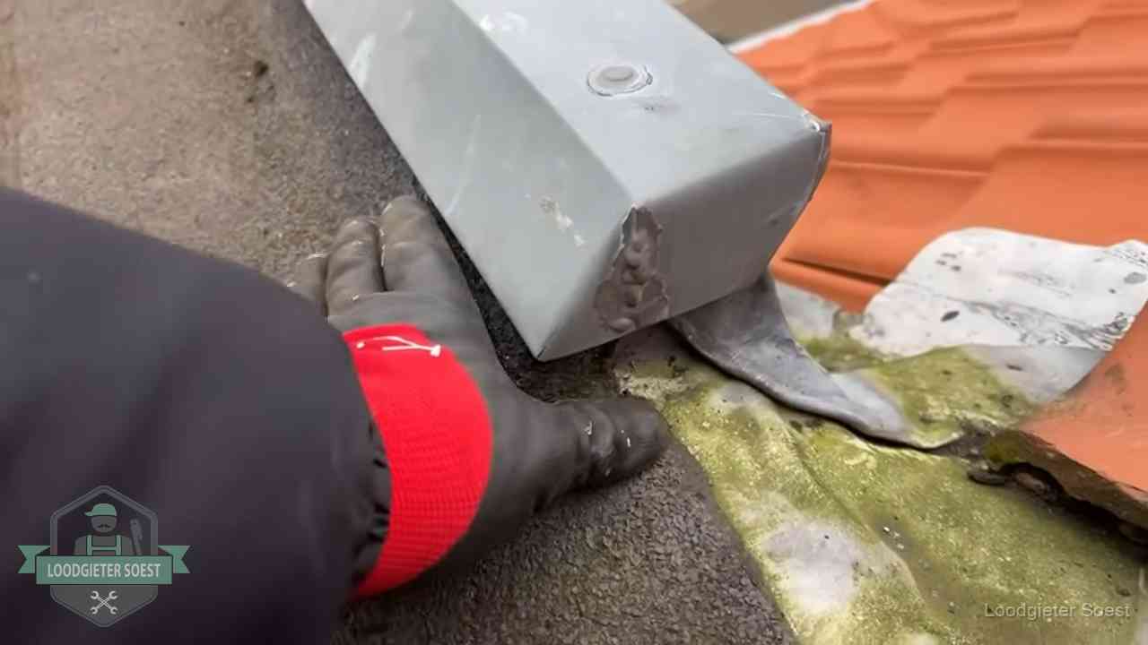 Controle van een zinken hemelwaterafvoer met loodslab bij dakpannen in Soest