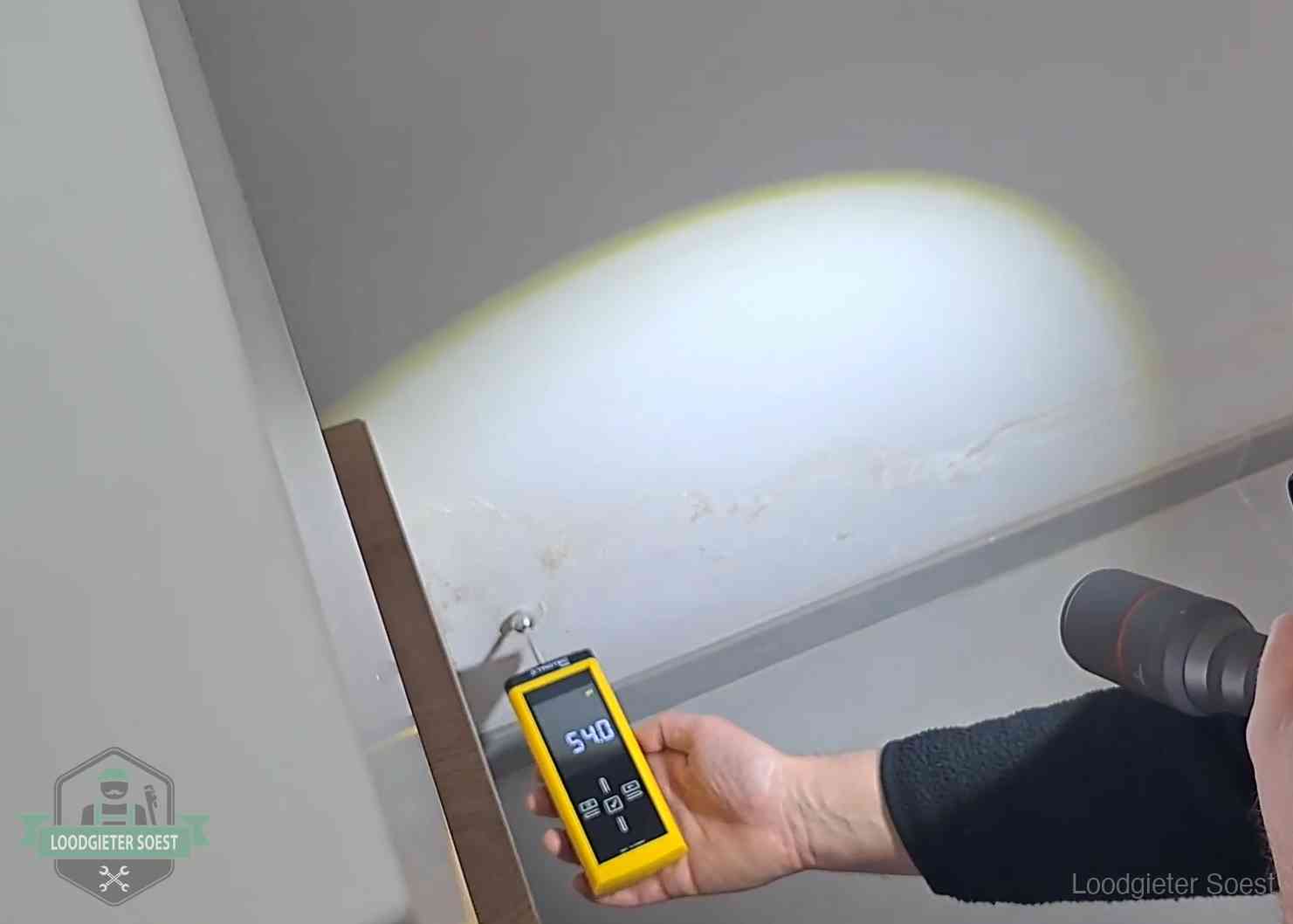 Vochtmeter tegen een natte wand met lekkagesporen in Soest