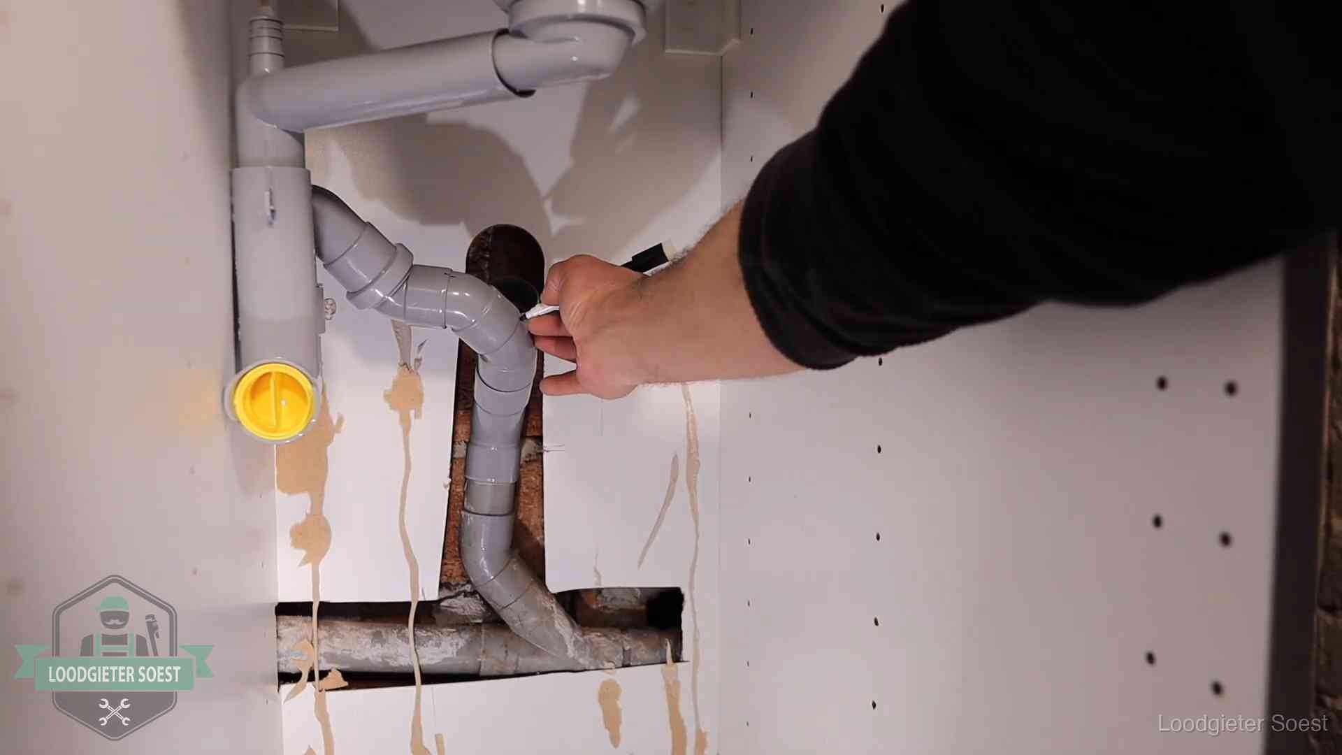 Loodgieter voor verhuurders en bedrijven in Soest Loodgieter markeert een pvc-afvoerbuis onder een gootsteen in Soest