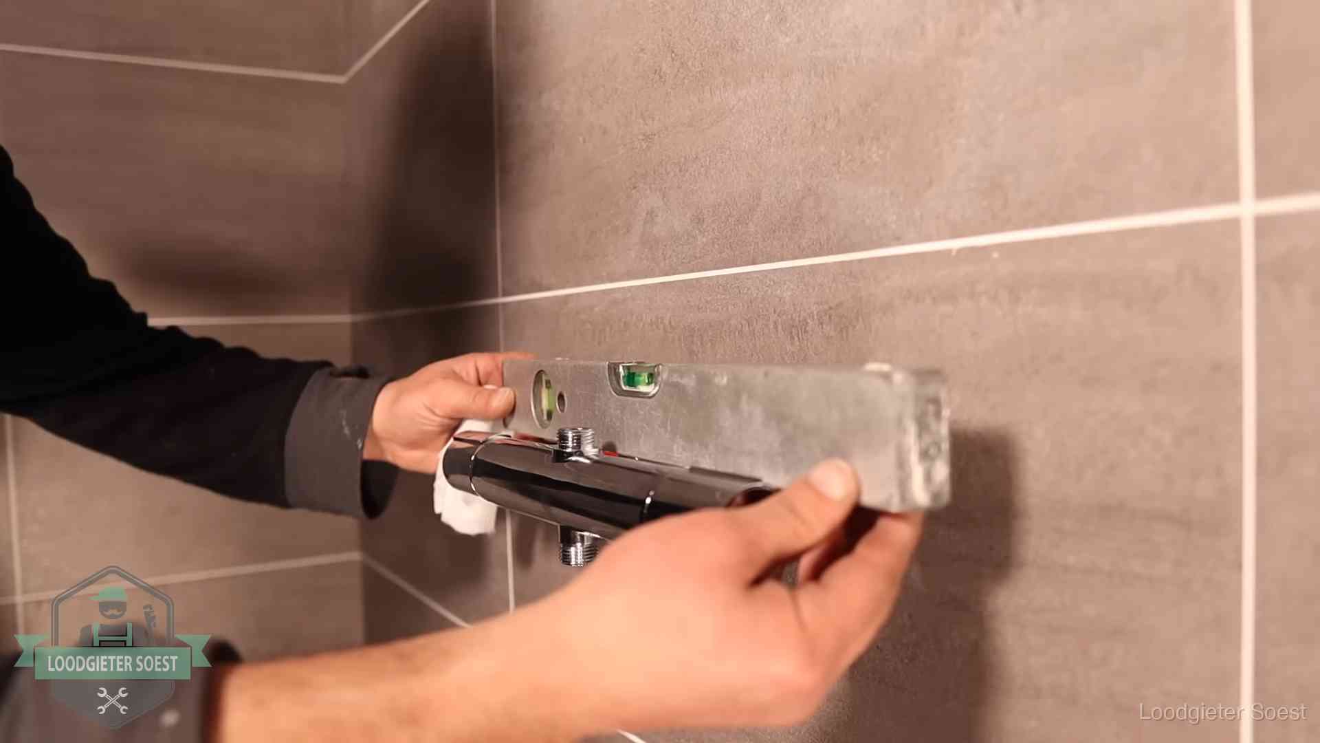 Loodgietersbedrijf voor sanitair in Soest Loodgieter lijnt een douchekraan uit met een waterpas in een woning in Soest