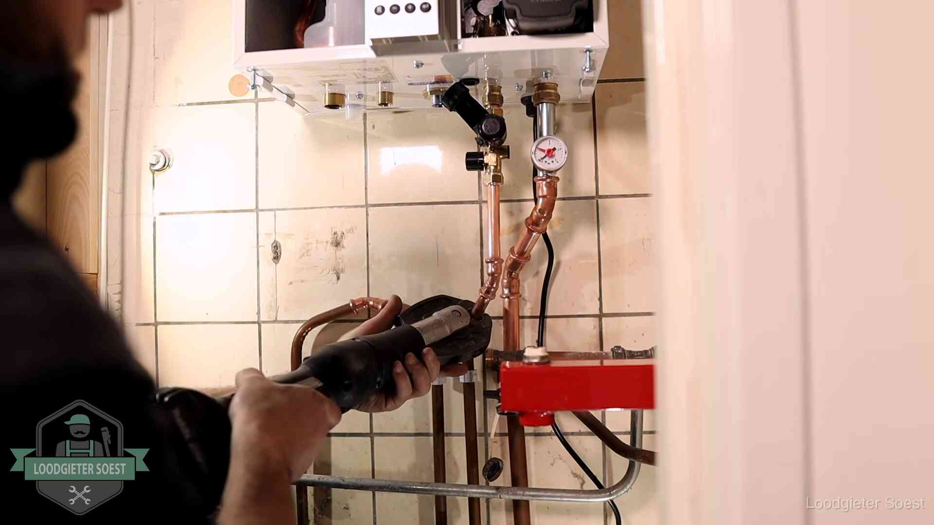 Monteur werkt aan de leidingen onder een cv-ketel in Soest