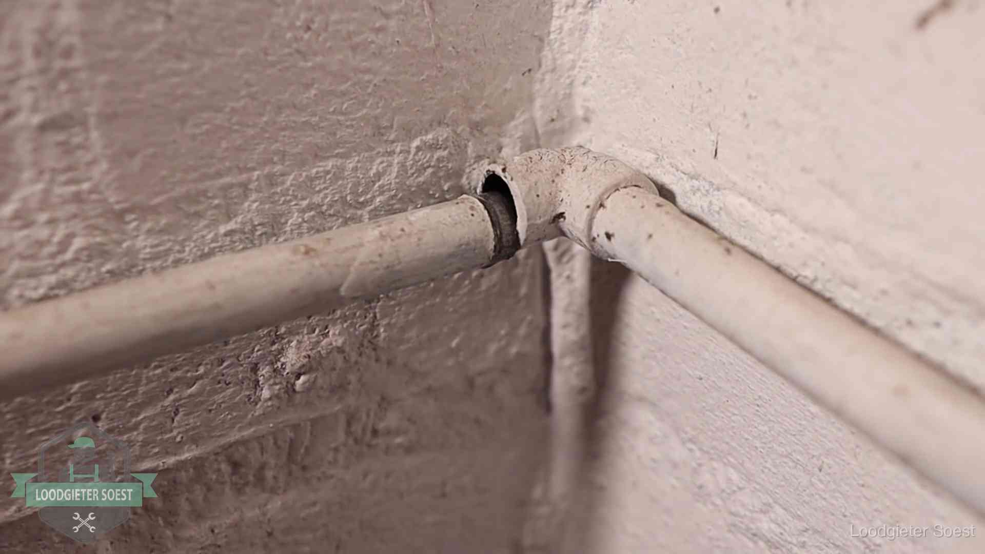 Oude geverfde waterleiding met een losliggende fitting in een woning in Soest