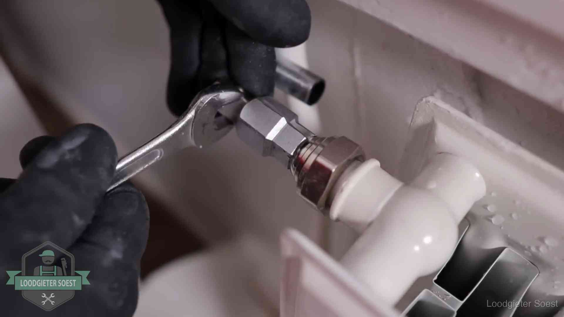 Steeksleutel draait een wartelkoppeling op een radiatorkraan aan in Soest