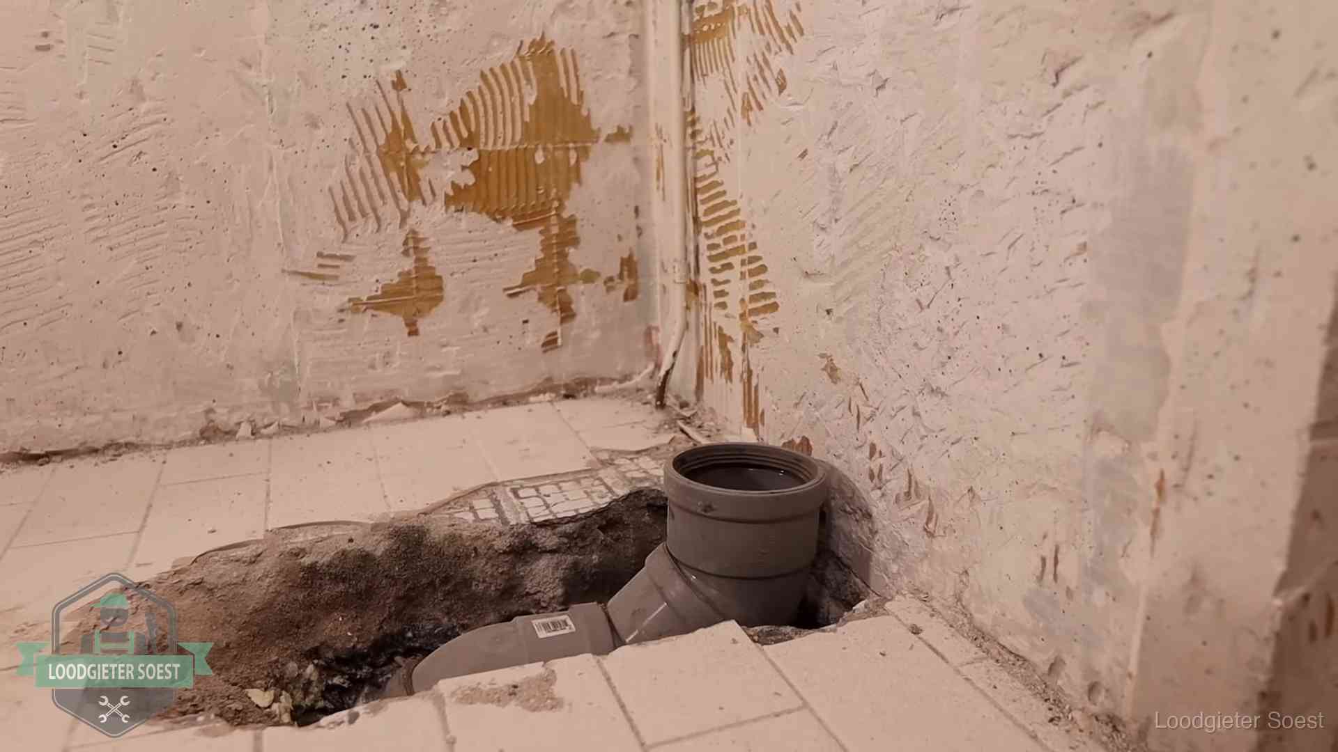 Verzakt riool herstellen in Soest Opengebroken vloer met een nieuwe pvc-rioolbocht in een gegraven sleuf in Soest