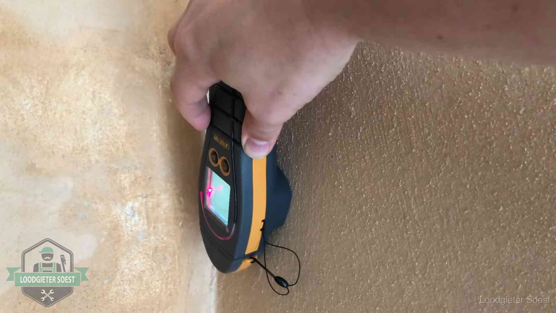 Vochtmeter tegen een muur met vochtplekken tijdens het opsporen van een daklekkage in Soest