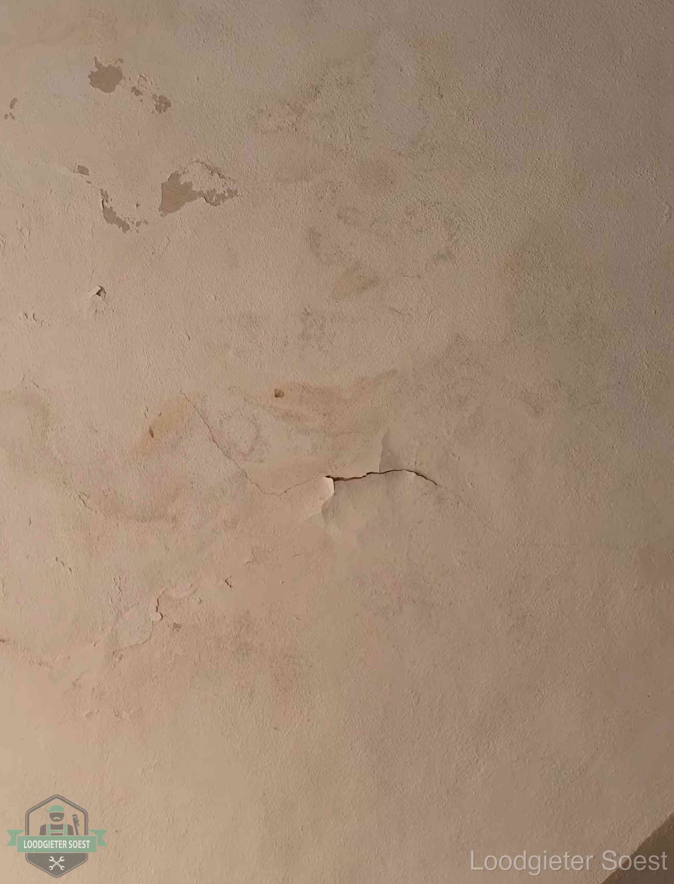 Vochtkringen en afbladderende verf op een plafond in Soest, schade voor het meetrapport en de verzekering