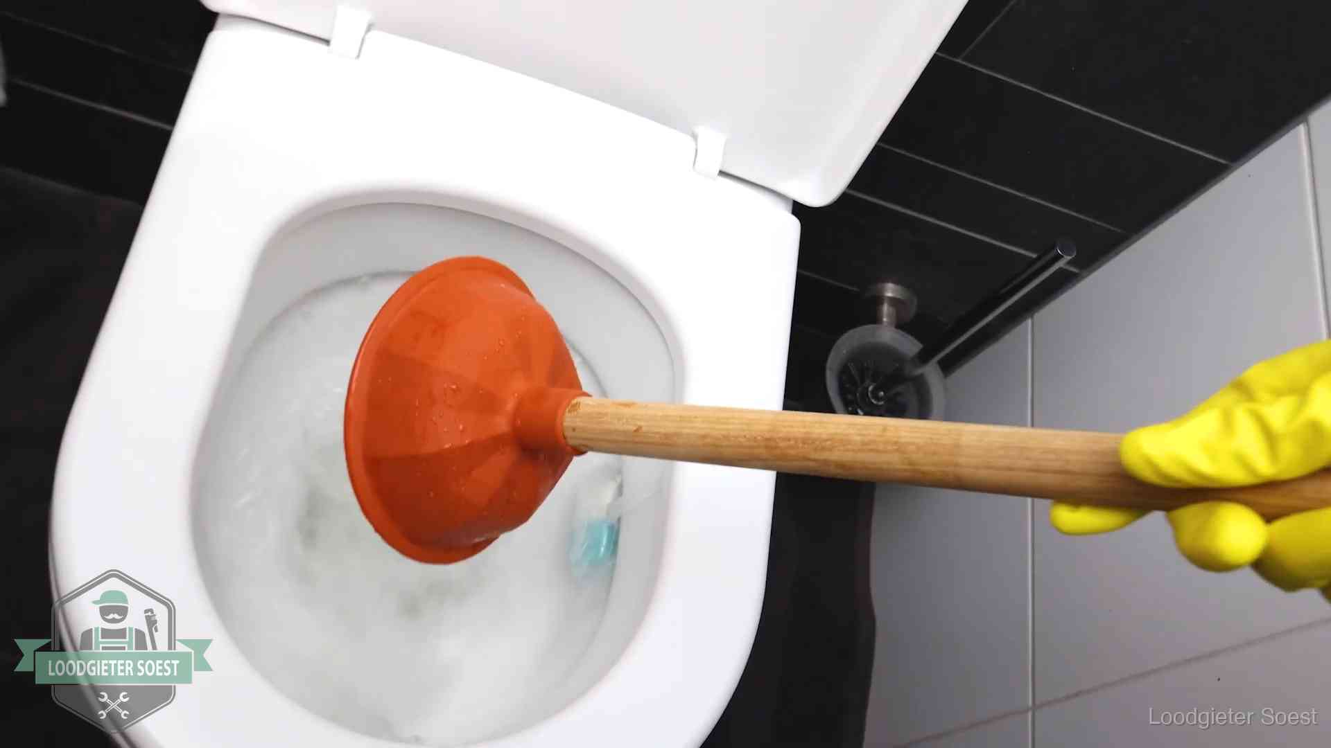 Plopper wordt in de wc-pot gedrukt bij het ontstoppen van een toilet in Soest